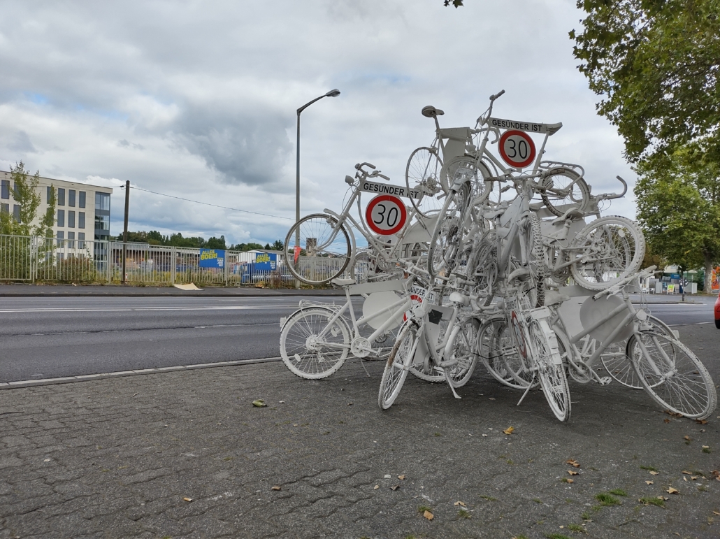 Fahrradskulpur mit Geisterfahrrädern und Tempo 30 ist gesünder Schildern