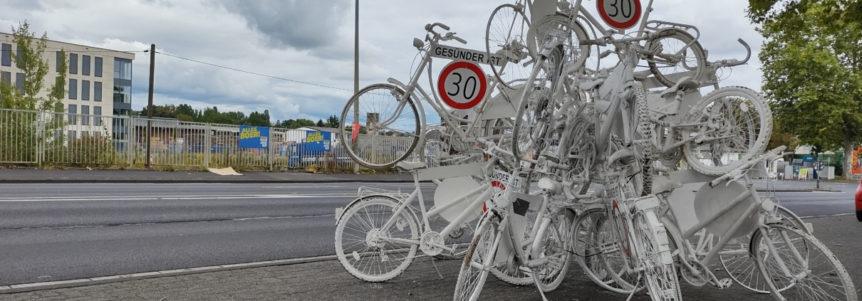 Fahrradskulpur mit Geisterfahrrädern und Tempo 30 ist gesünder Schildern